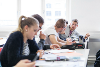 Fünf Studierende sitzen im Seminar an Tischen